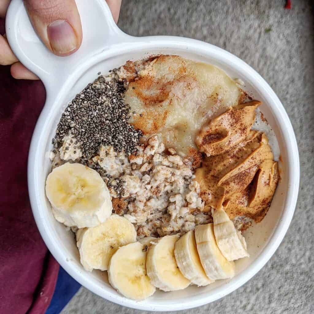 Cooked oatmeal topped with banana, nut butter, chia seeds and applesauce. An easy healthy breakfast