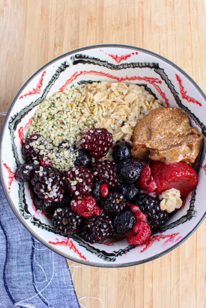 Cooked oatmeal topped with berries, nut butter, and seeds