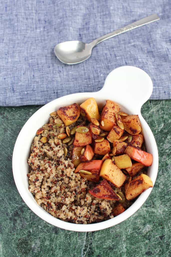 A bowl of coconut milk breakfast quinoa on a green granite cutting board