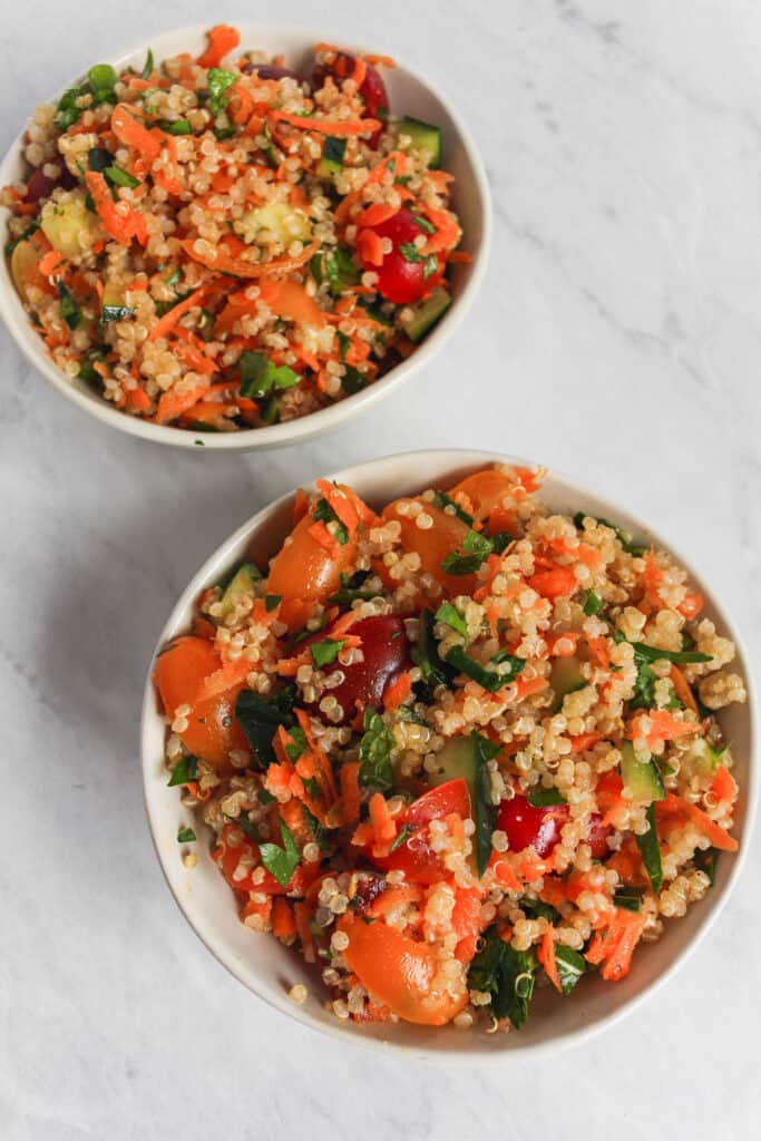 Two serving bowls filled with the quinoa tabbouleh salad on a marble background