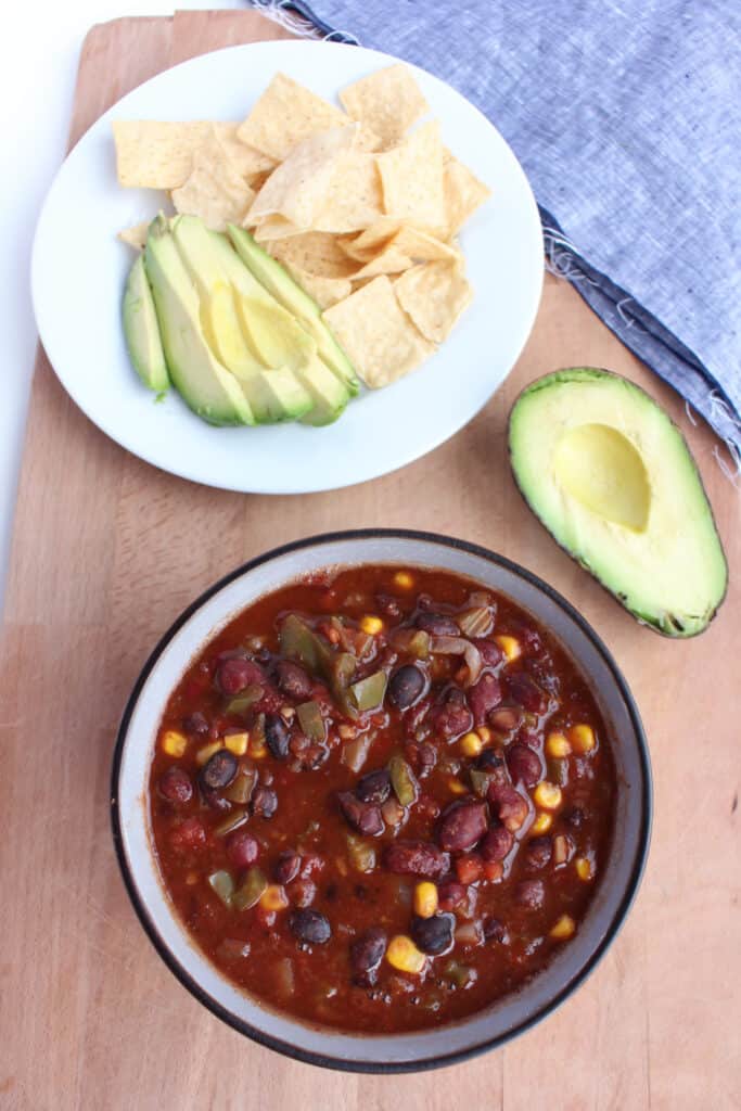 Bowl of chili with avocado and tortilla chips. A nutritious gluten free, vegan meal.
